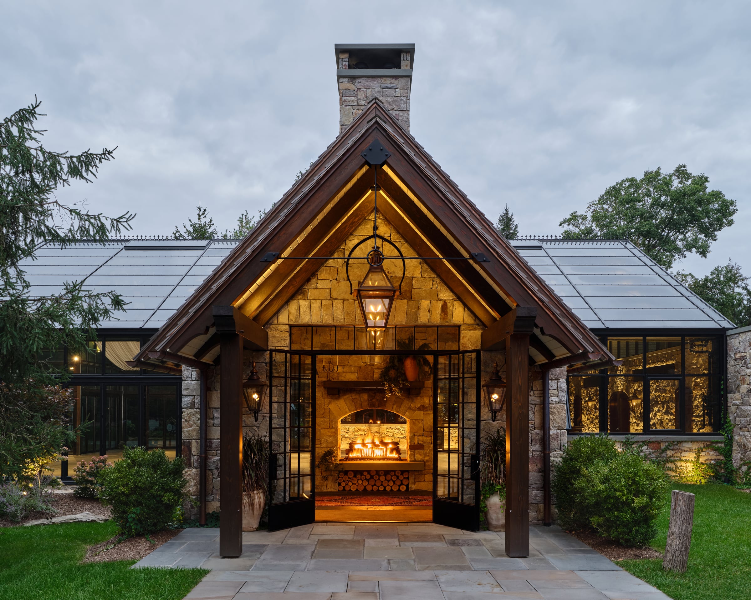 The Glasshouse at Cedar Lakes Estate at dusk, lanterns lit beneath the timber gable