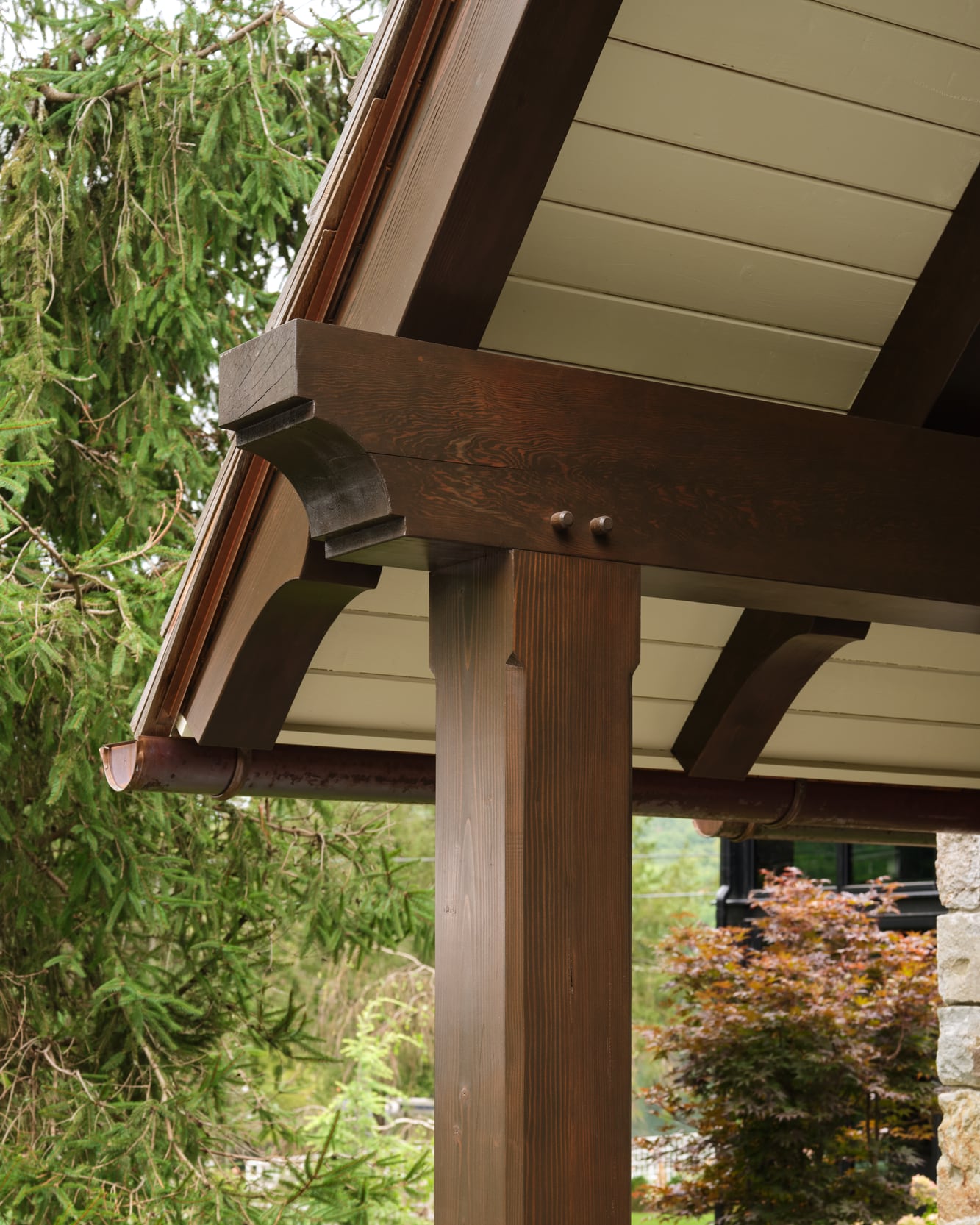 A timber post and bracket carrying the porch roof, trees beyond