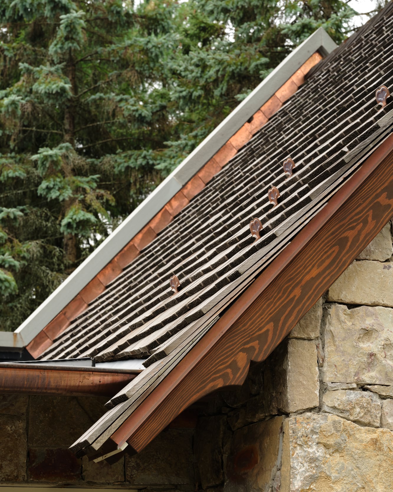 Scrolled rafter tails along the roof edge, roughed on the CNC and finished by hand
