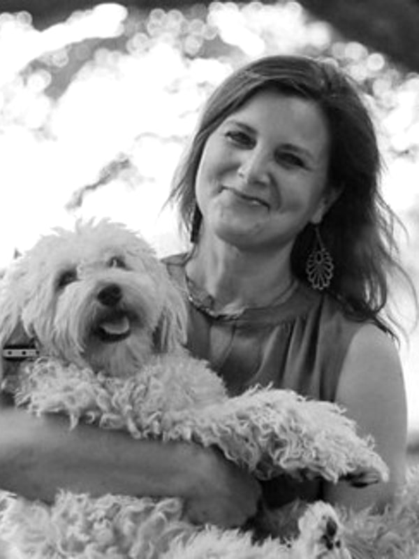 Connie Sickler holding her small white dog outdoors, black and white