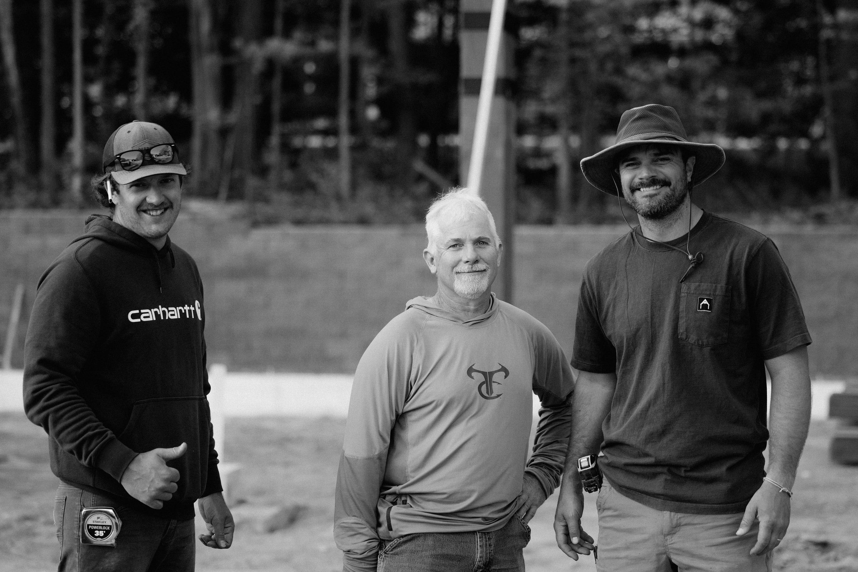 Three members of the raising crew on site, smiling, black and white