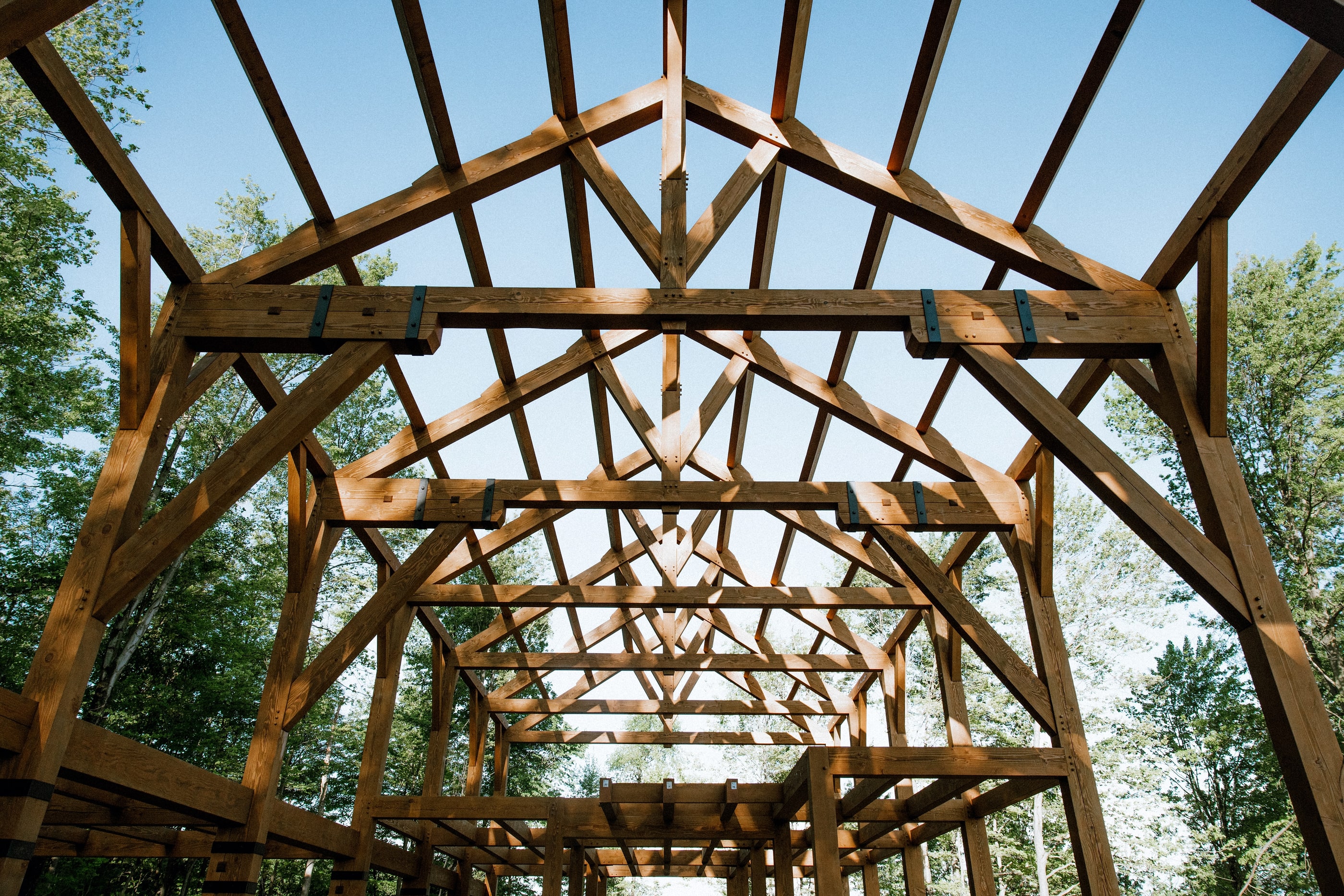 Looking down the length of the frame from inside, trusses in a row toward the ridge