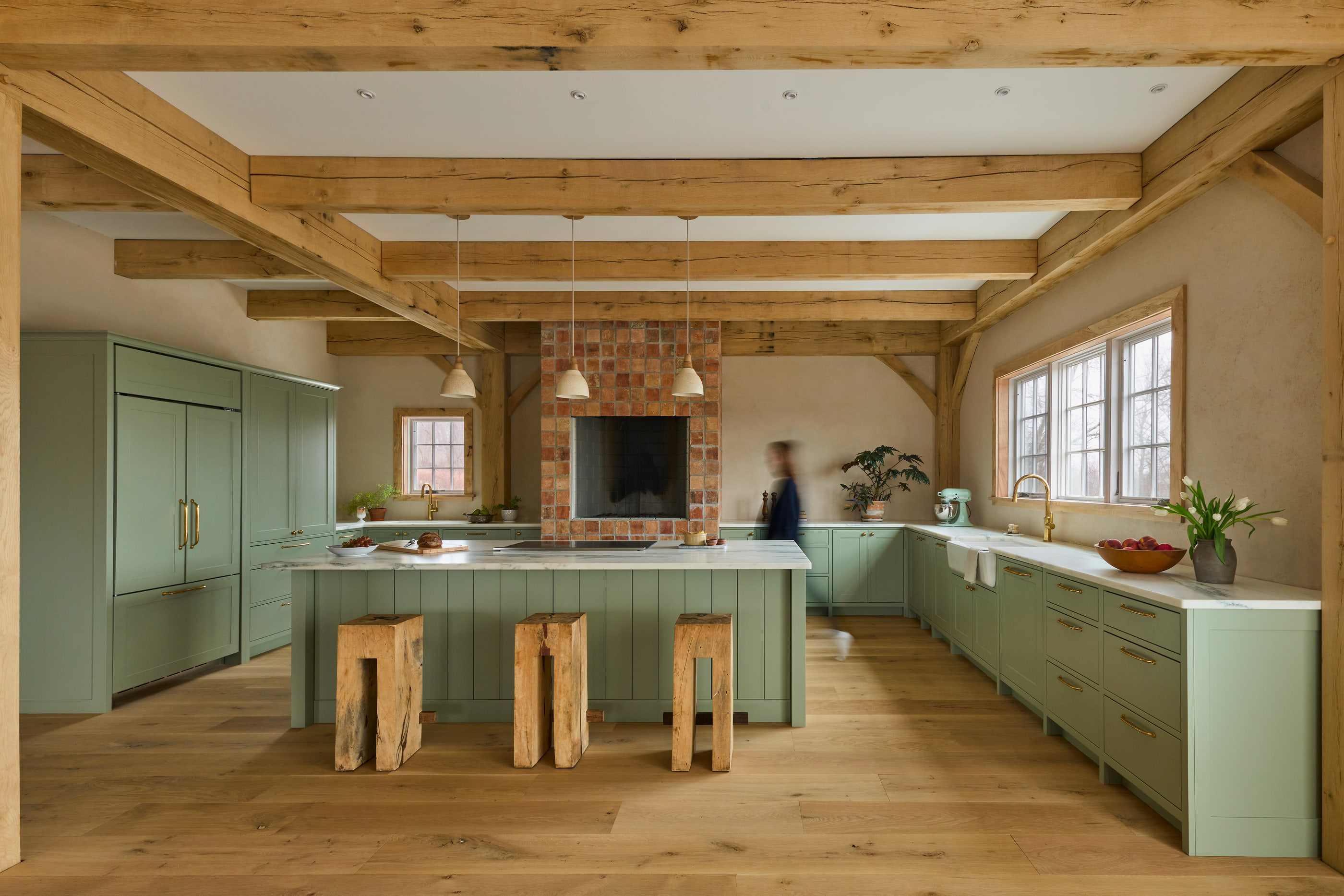 A white oak timber frame kitchen, the beams running over a pale green island and cabinets