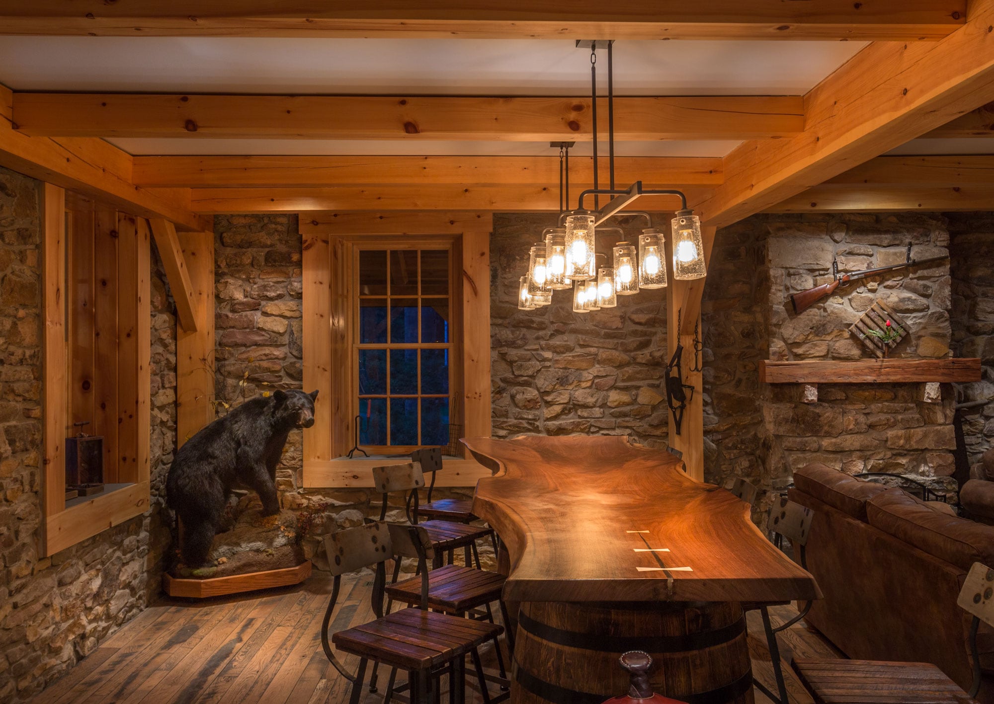 A live-edge bar table under the timber frame, stone walls and a deep-set window behind