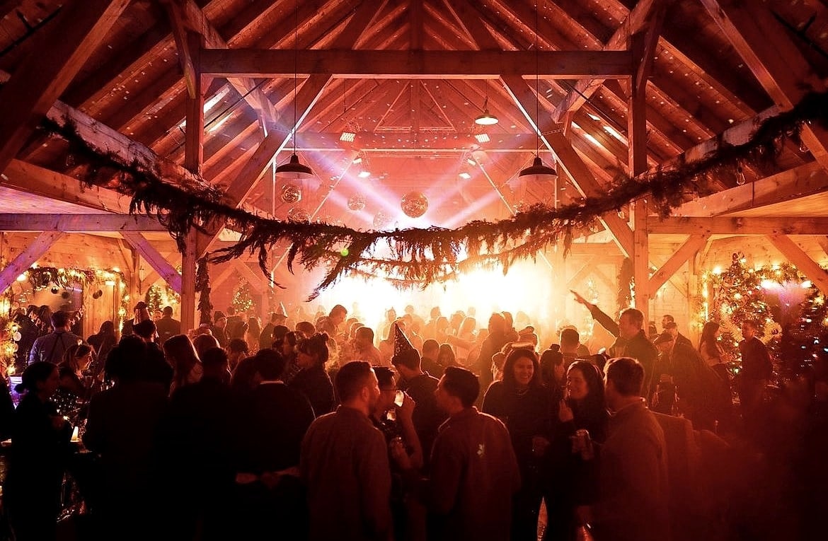 A party in the finished barn, greenery hung across the frame and the floor full