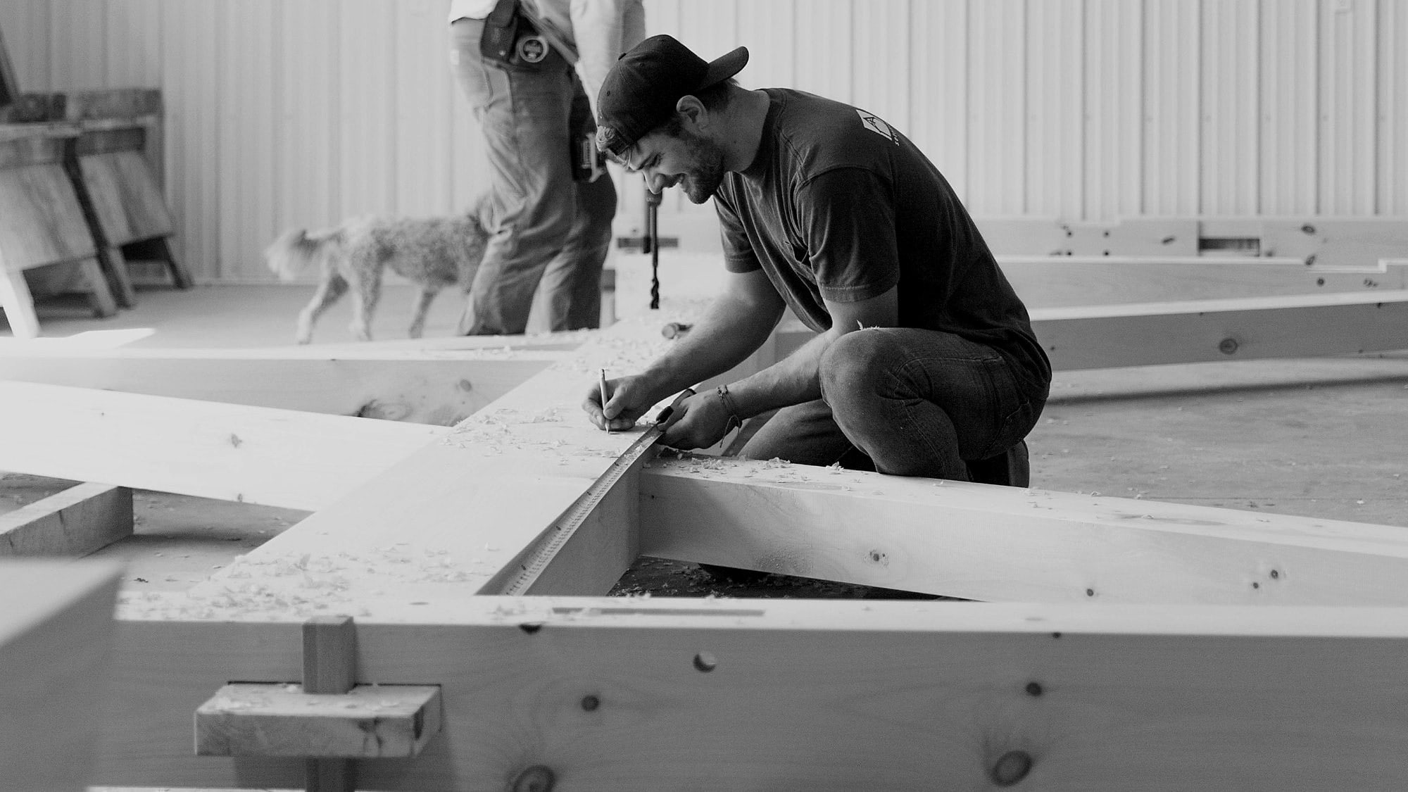 A framer marking a pine timber in the shop, black and white