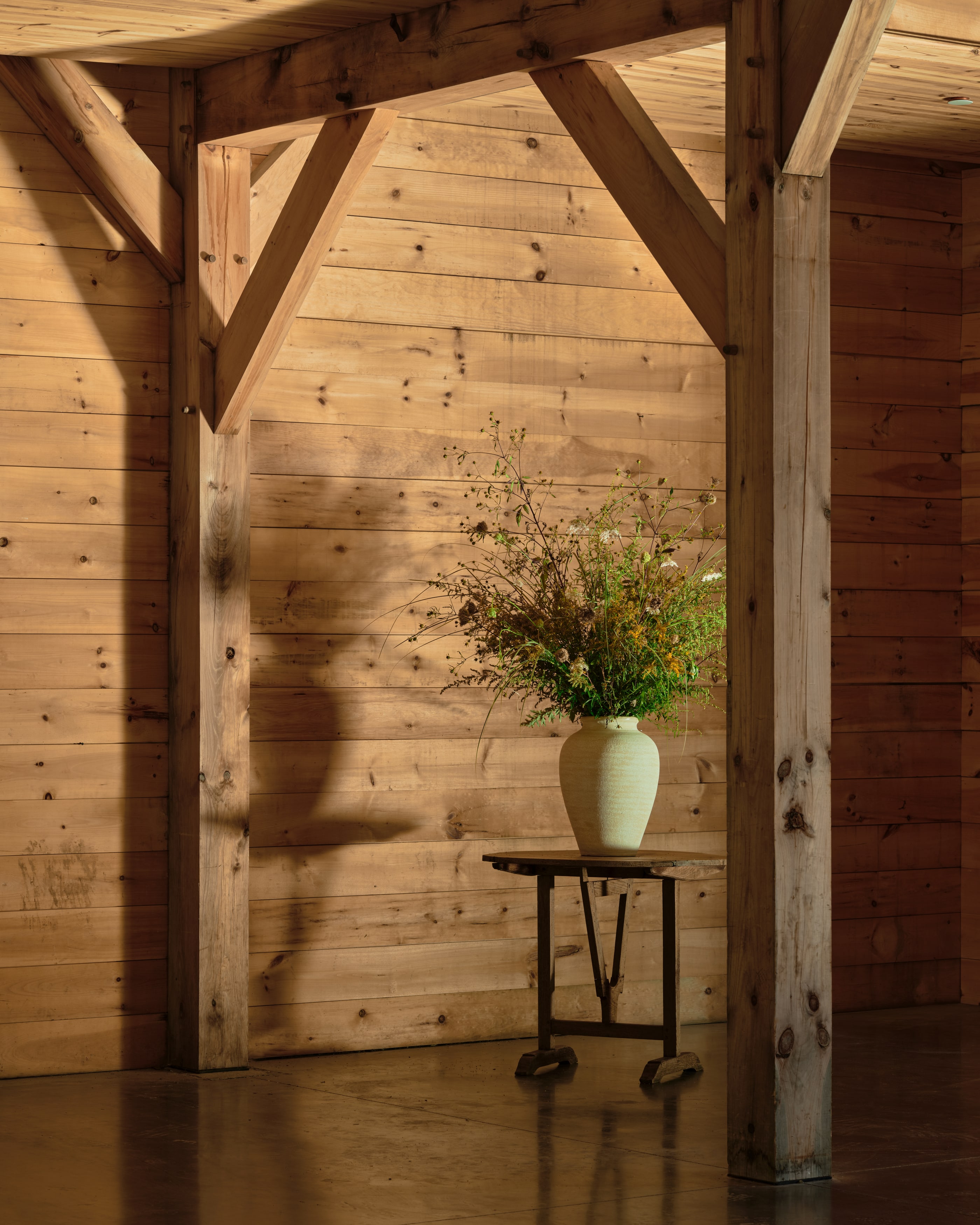 An aisle post with its braces, a vase of wildflowers on a table in the low light