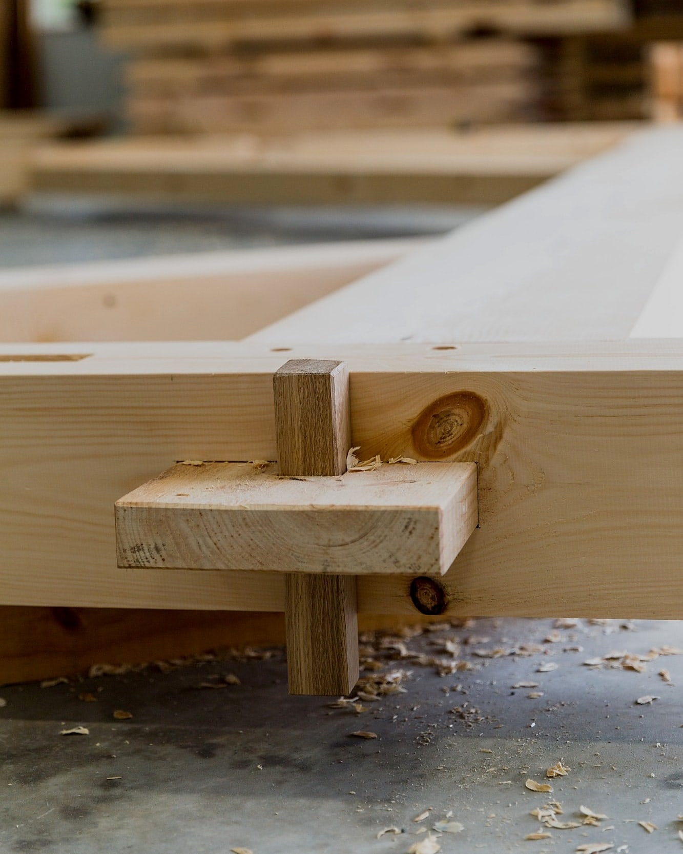 An anchor beam’s through-tenon test-fit in the shop, locked with a wedge