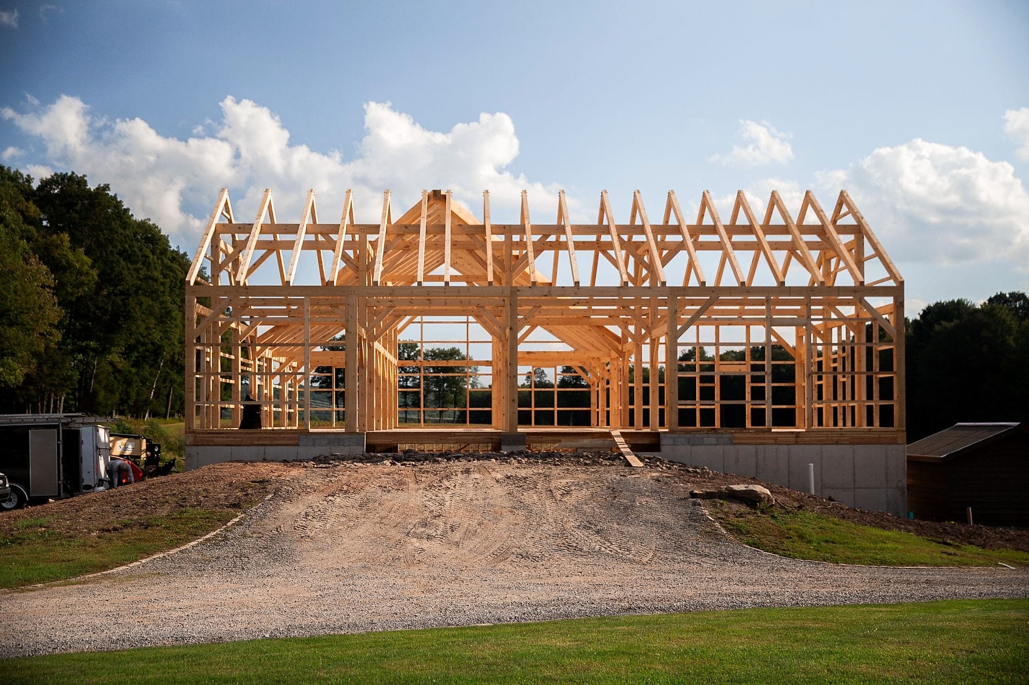 The Kacin barn frame standing on its foundation, its trusses against a summer sky