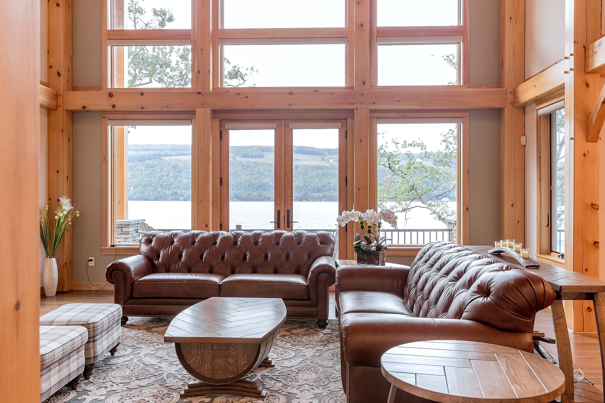 The great room's two-story timber window wall, straight on, the lake and the far shore beyond