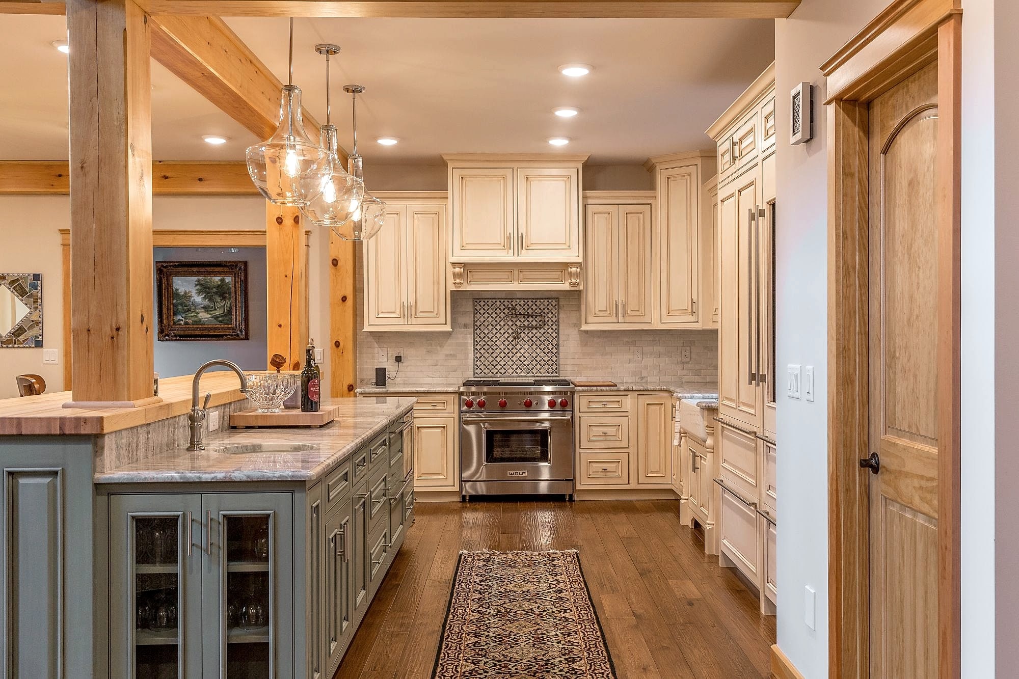 Kitchen framed by timber posts and beams, pendants over the island