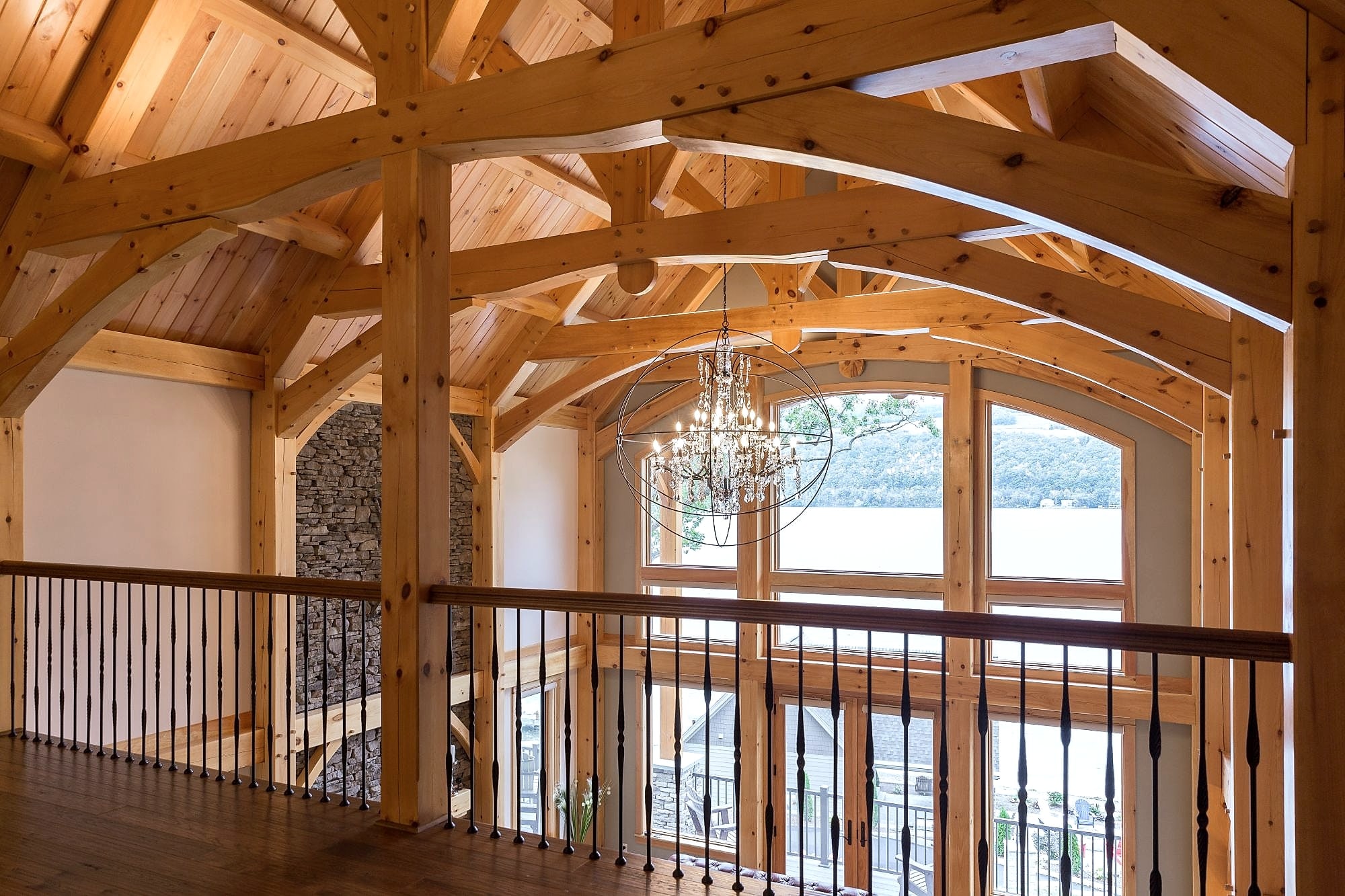 From the loft: curved trusses running toward the arched window and the lake