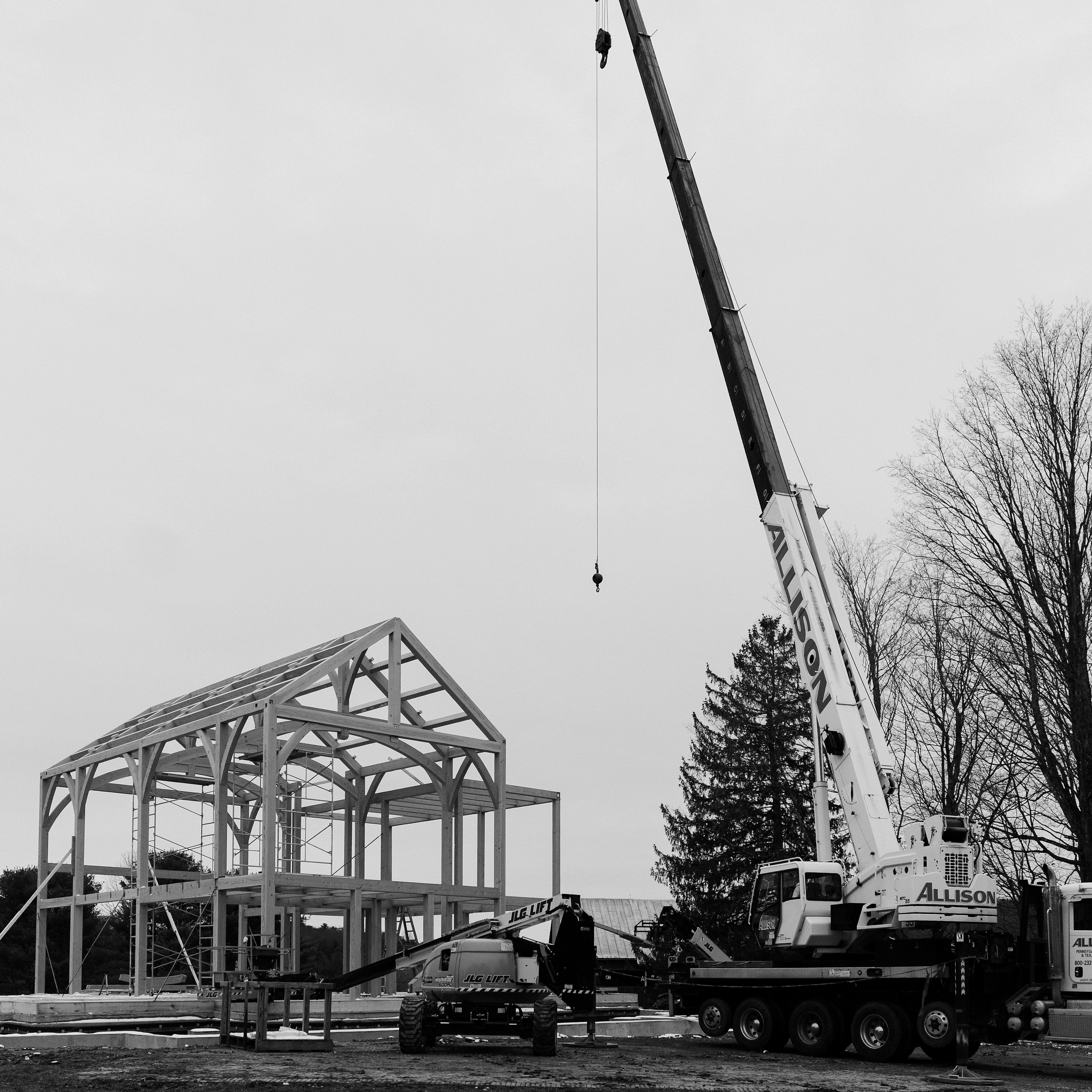 The crane on site, setting timbers into the frame, black and white