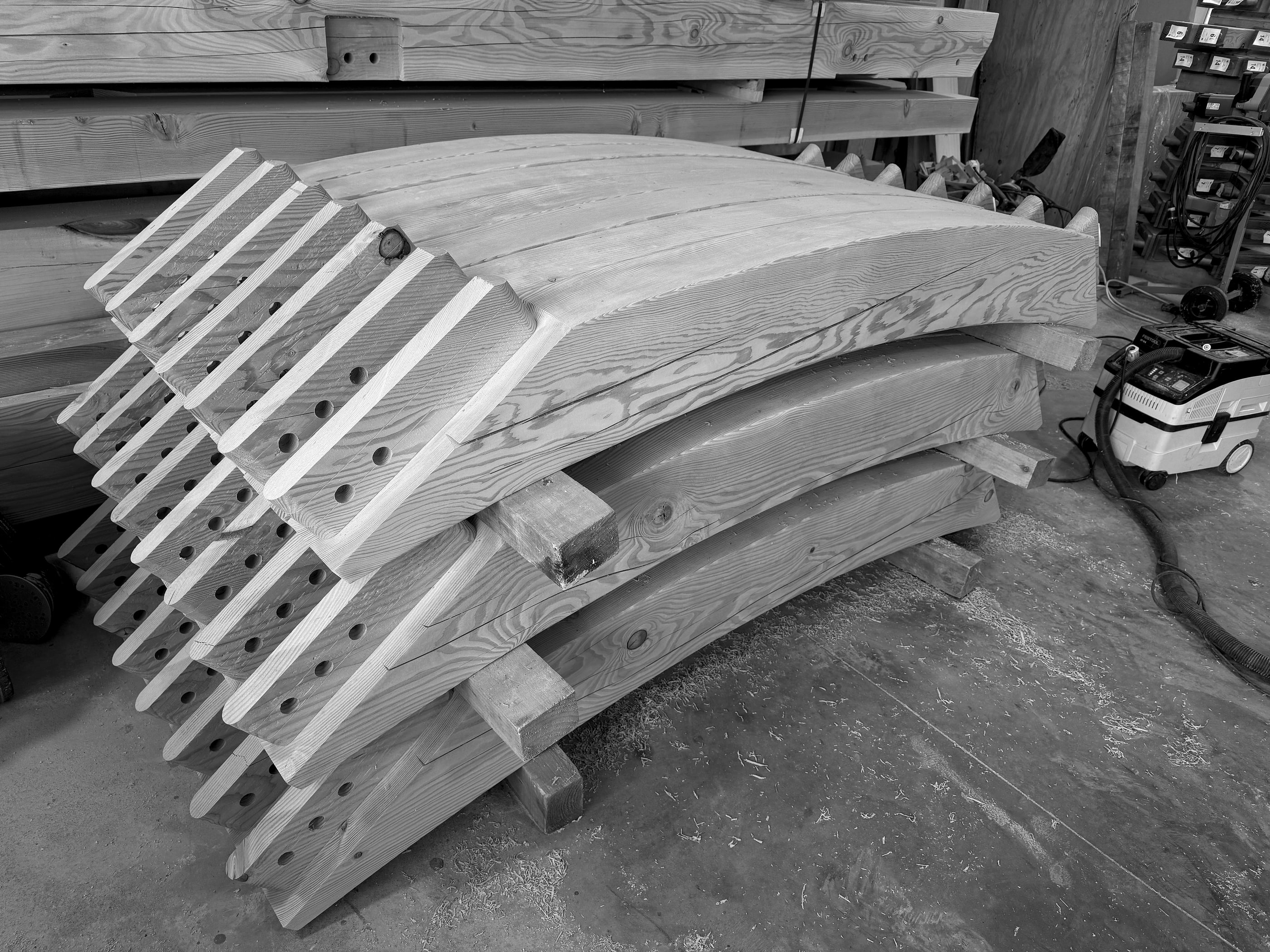 Curved knee braces, solid-sawn in the shop, stacked with their tenons cut, Mendenhall Hill