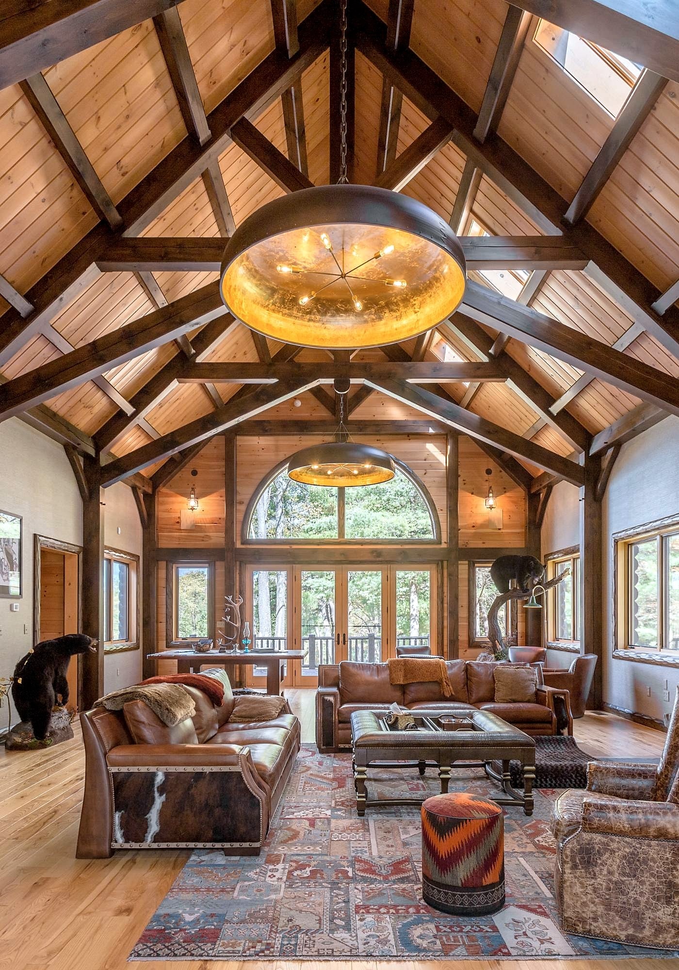 The vaulted great room, seen straight on, with its paired chandeliers and timber trusses