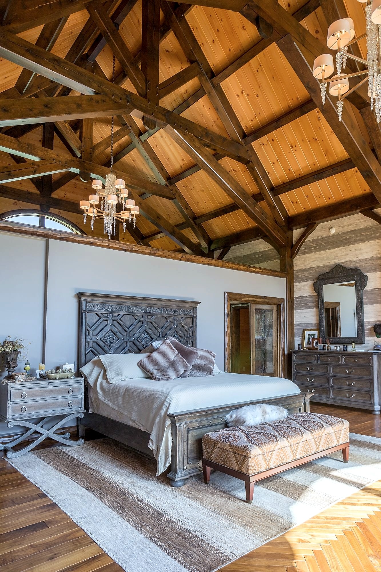 The bed under the master suite's trusses, chandelier overhead