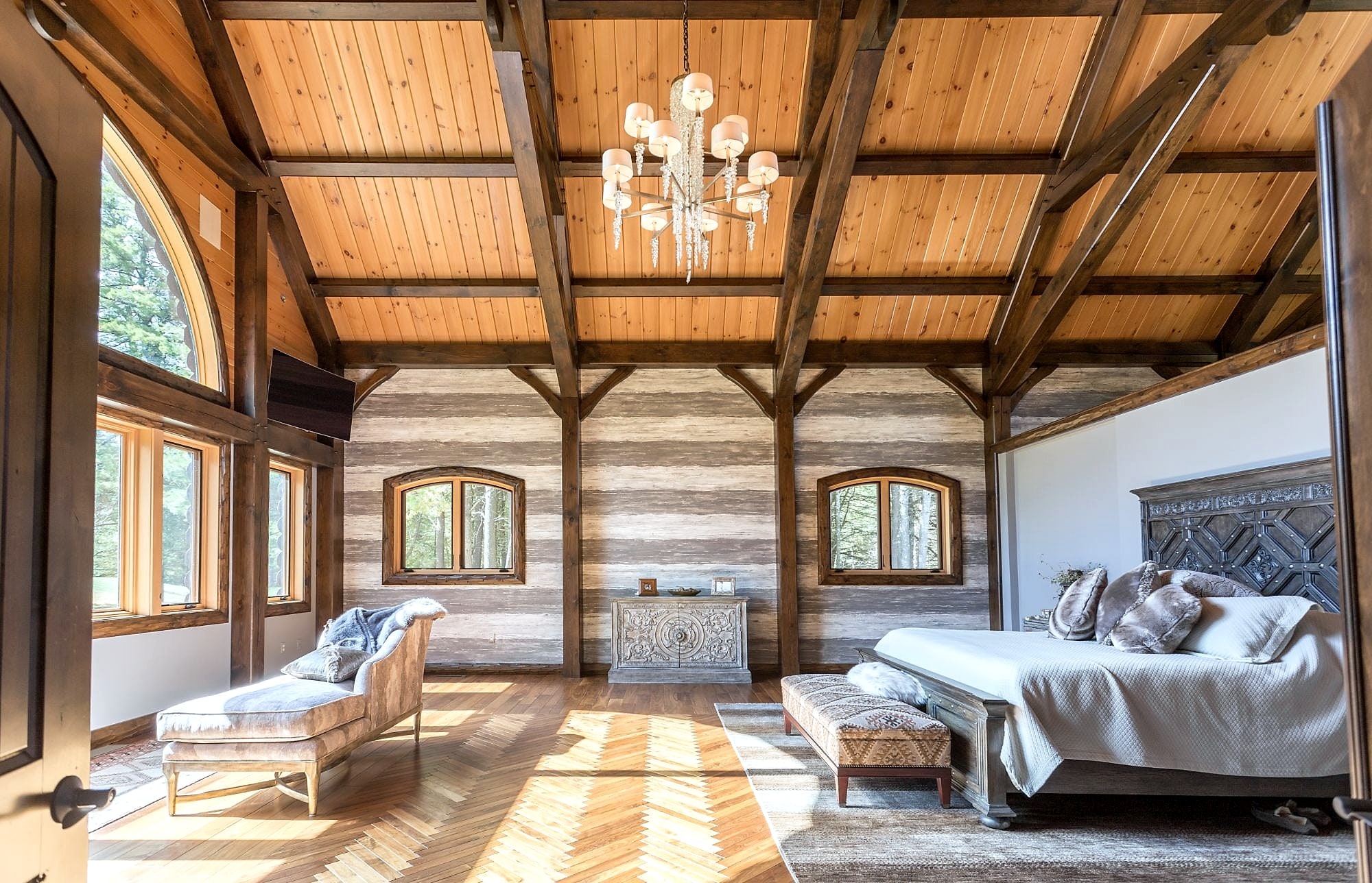 The master suite from its doorway: chandelier hung from the frame, herringbone floor