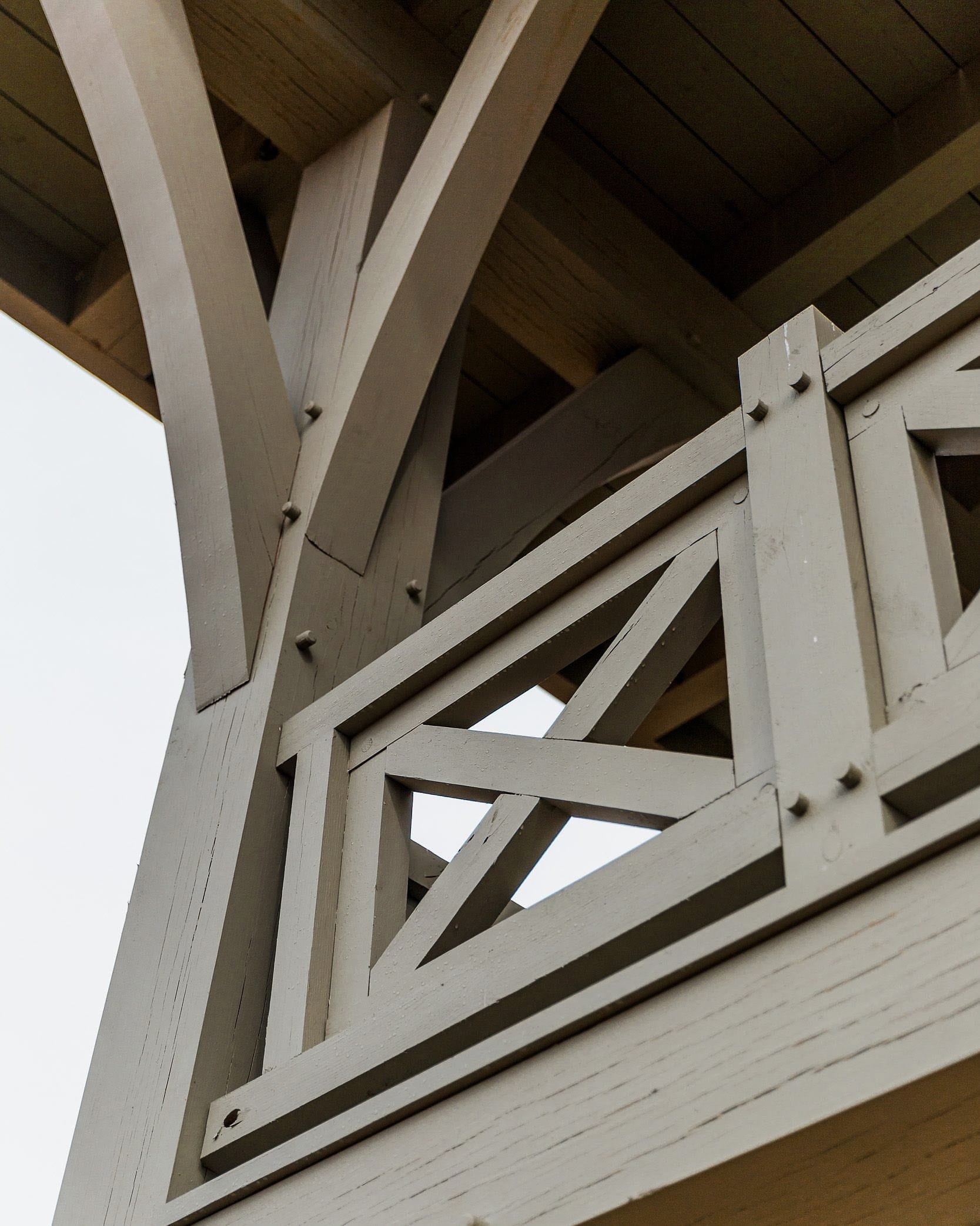 Curved braces meeting a post beside a pegged X-railing panel