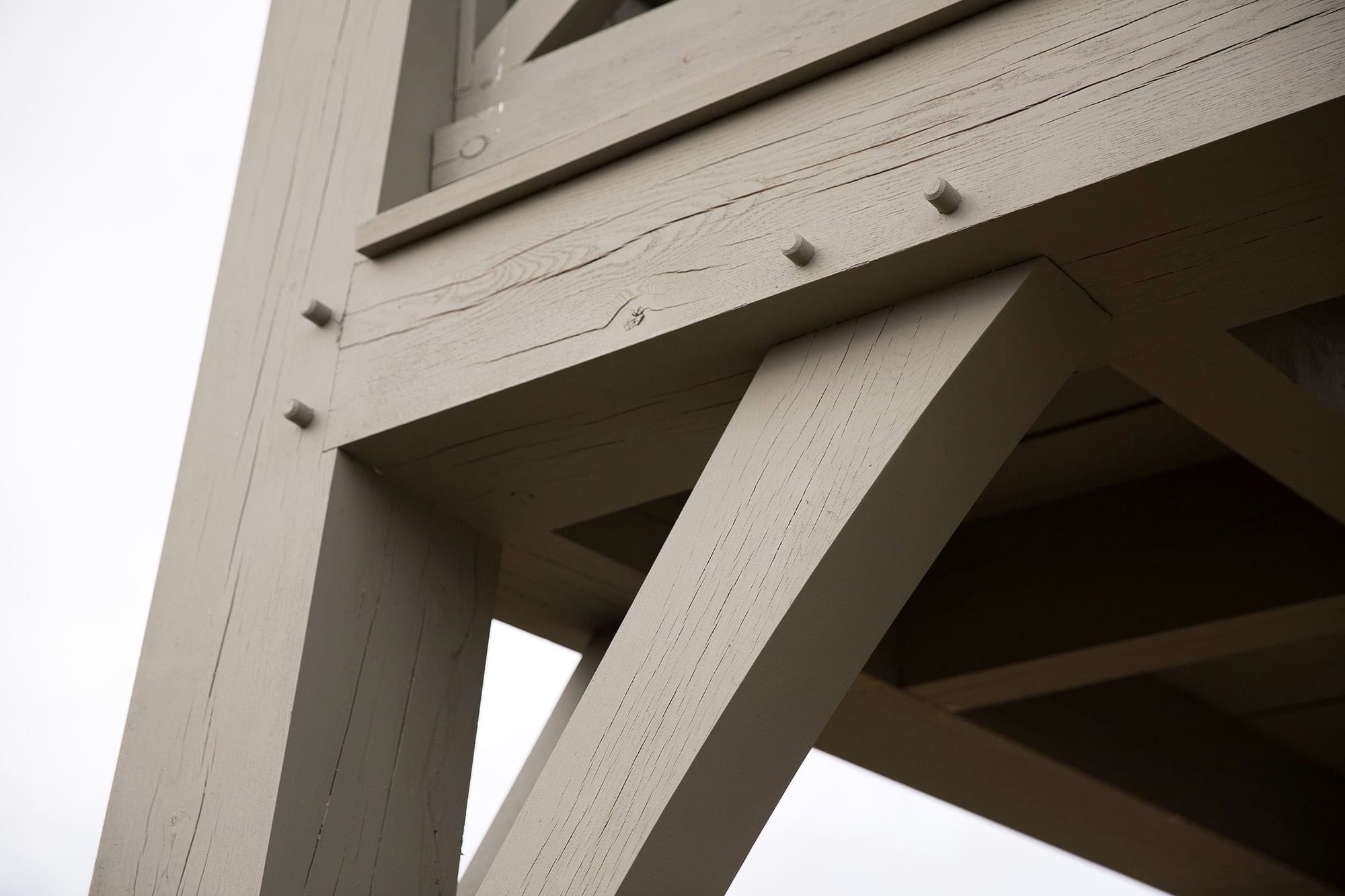 A post, beam and brace meeting at a pegged corner, seen from below