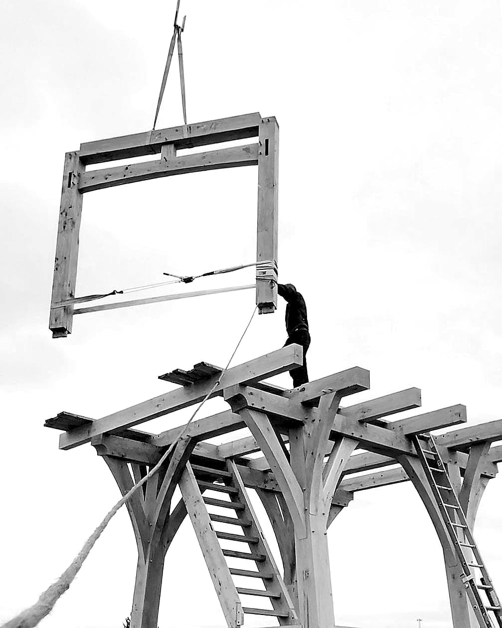 A wall frame on the telehandler’s jib, guided onto the top of the tower, black and white