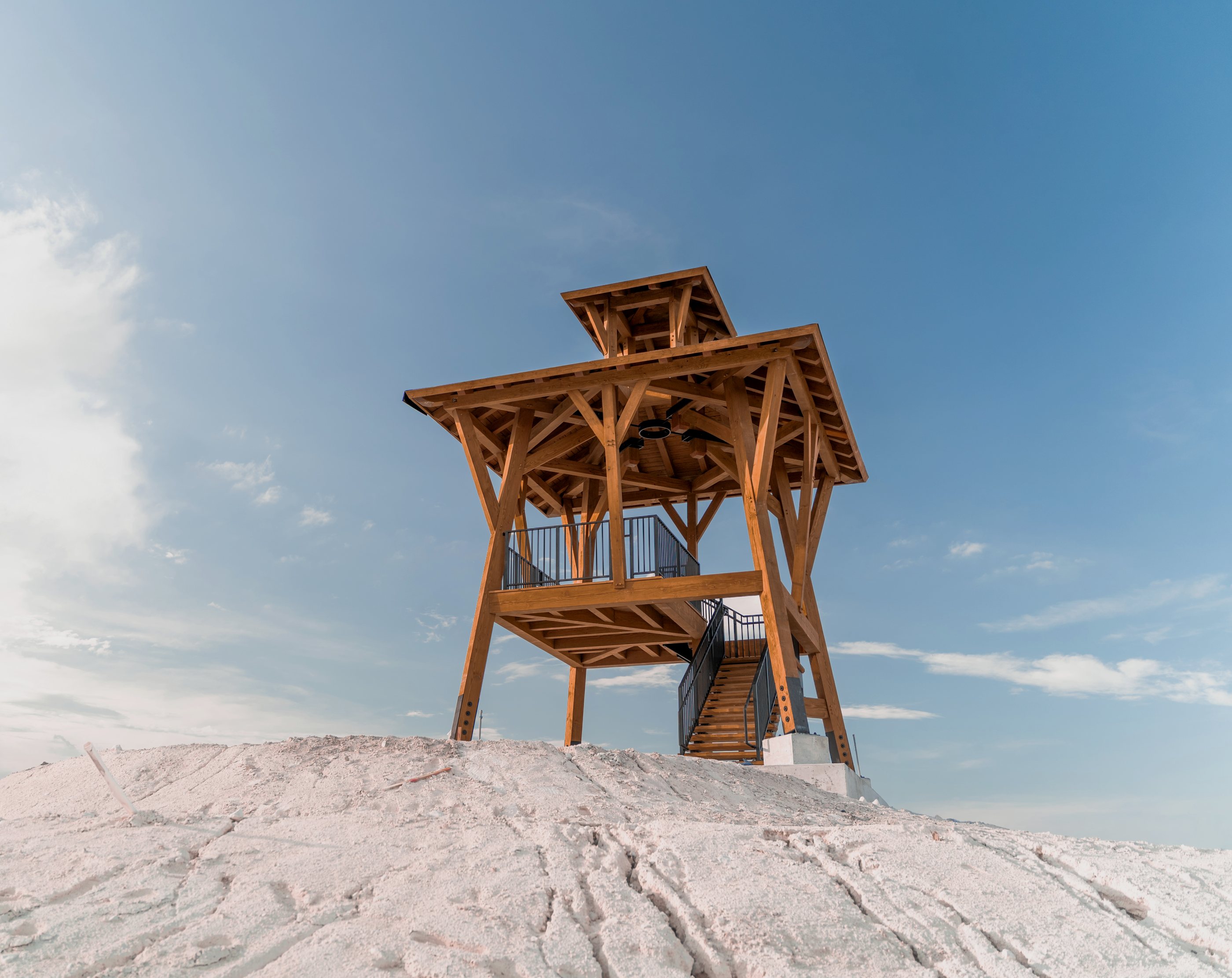 The Parkland observation tower on its mound, the timber frame and stair against a blue sky