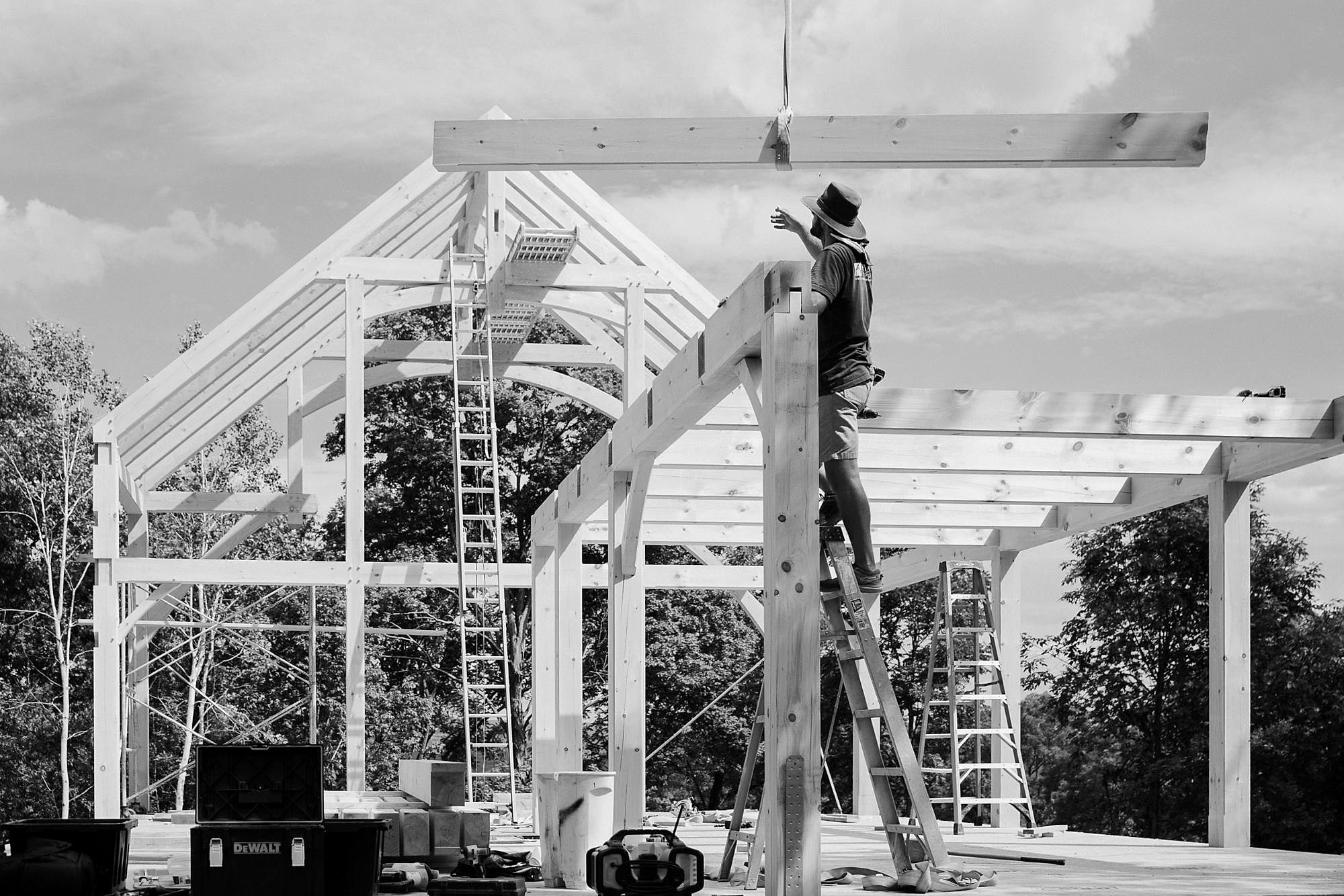 Guiding a beam down from the crane onto a post, from a ladder