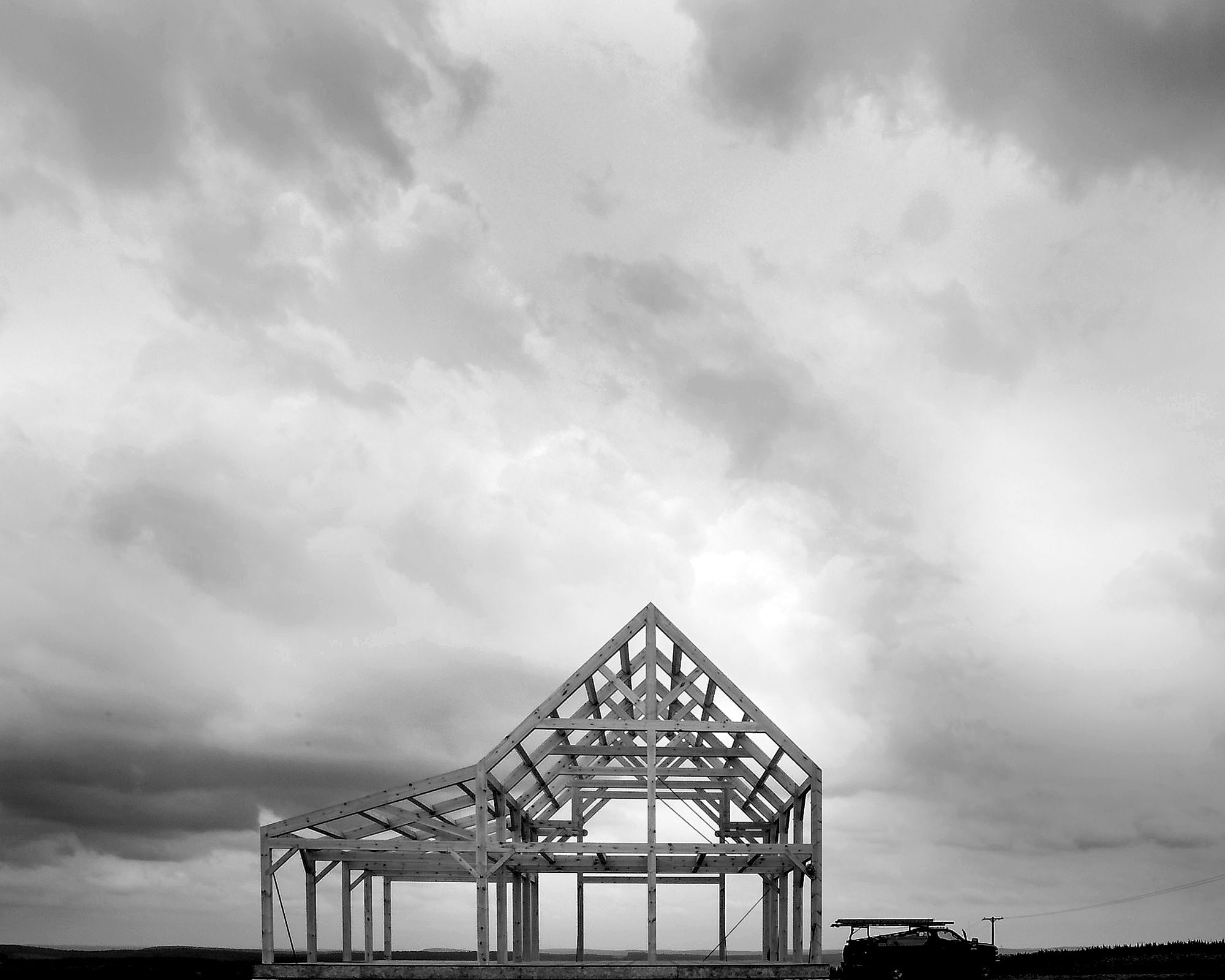 A raised frame alone on a hilltop under a big sky, the truck parked beside it