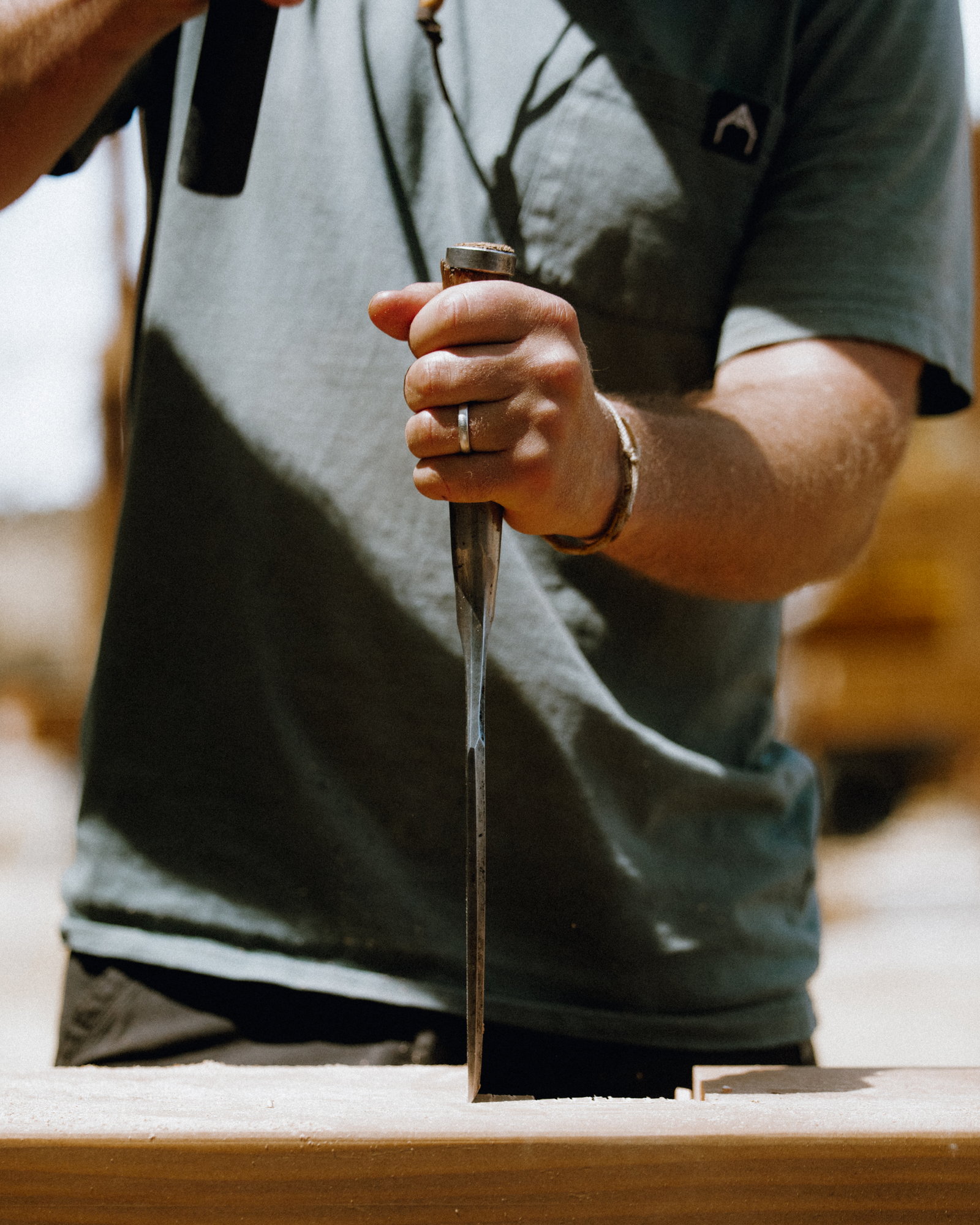 A framer driving a chisel into a mortise in the shop