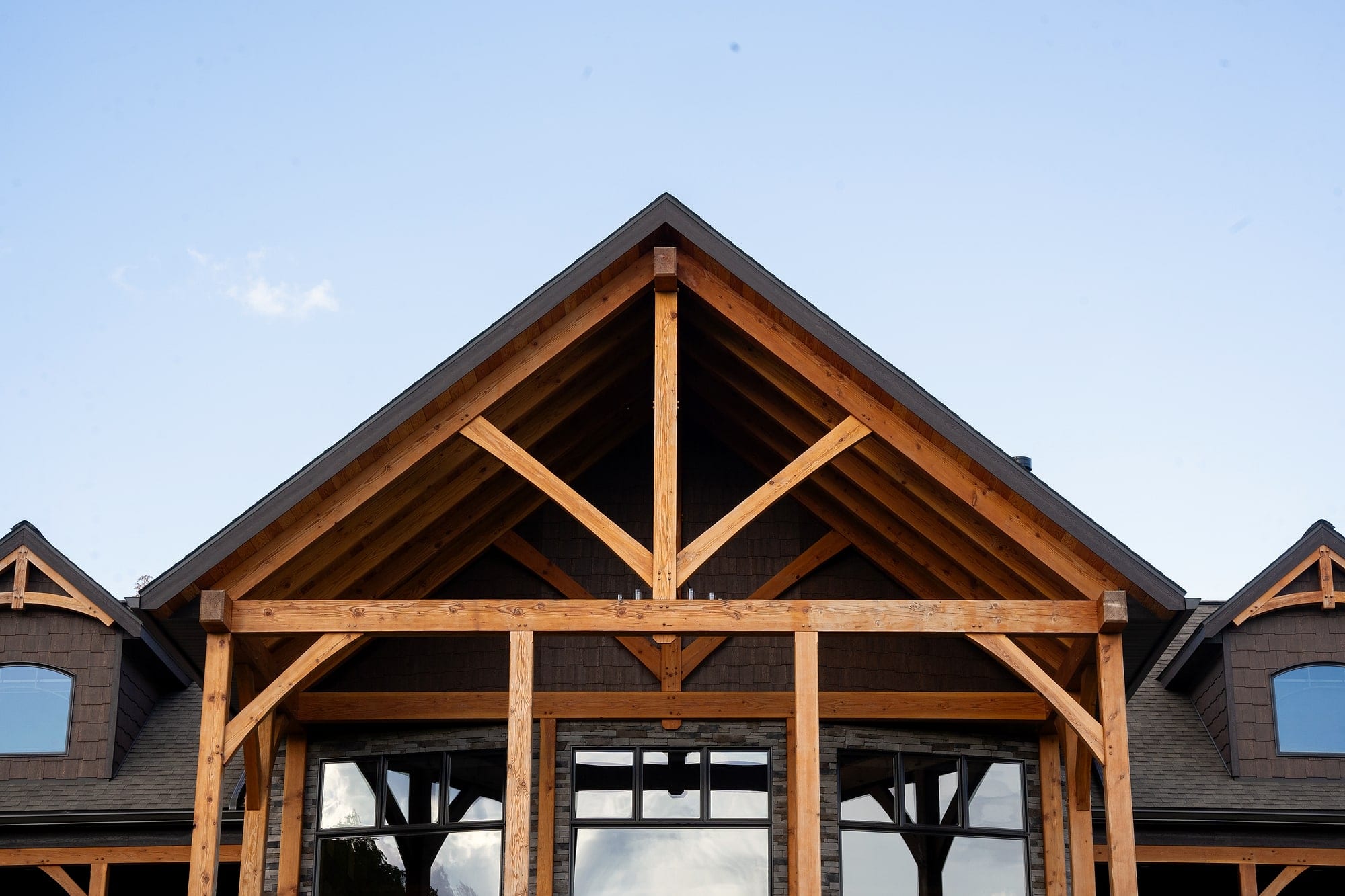 The front gable: a timber king post truss with braces over the porch posts, against a clear sky
