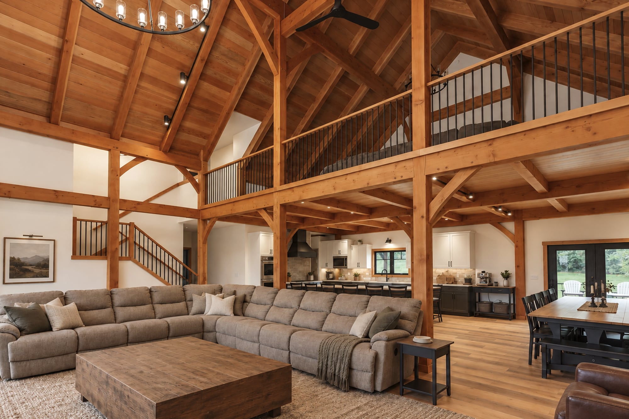 The great room open to the roof: timber bents, the loft over the rear of the room, and the kitchen beneath it