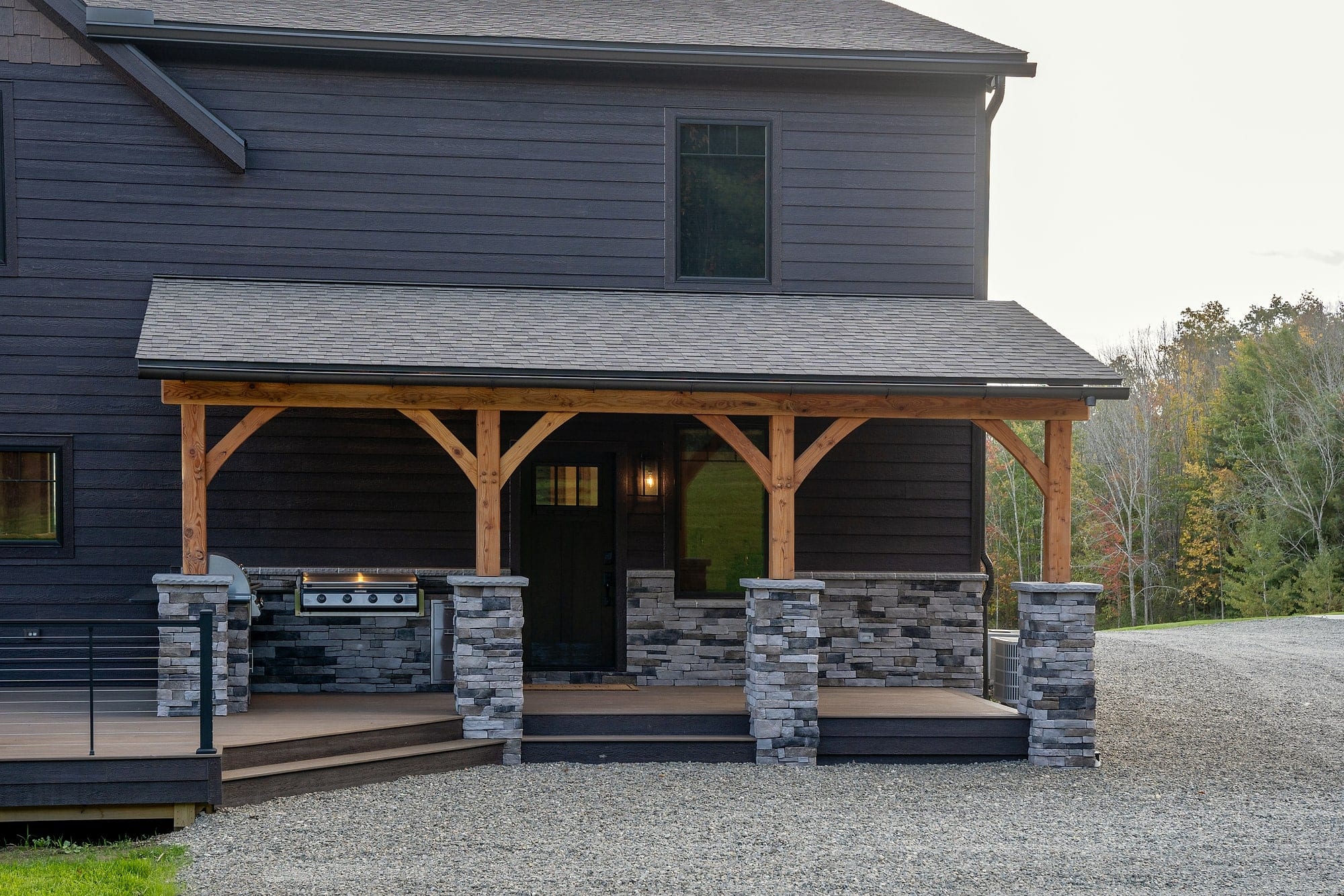 The side porch: braced timber posts on stone piers along the dark siding